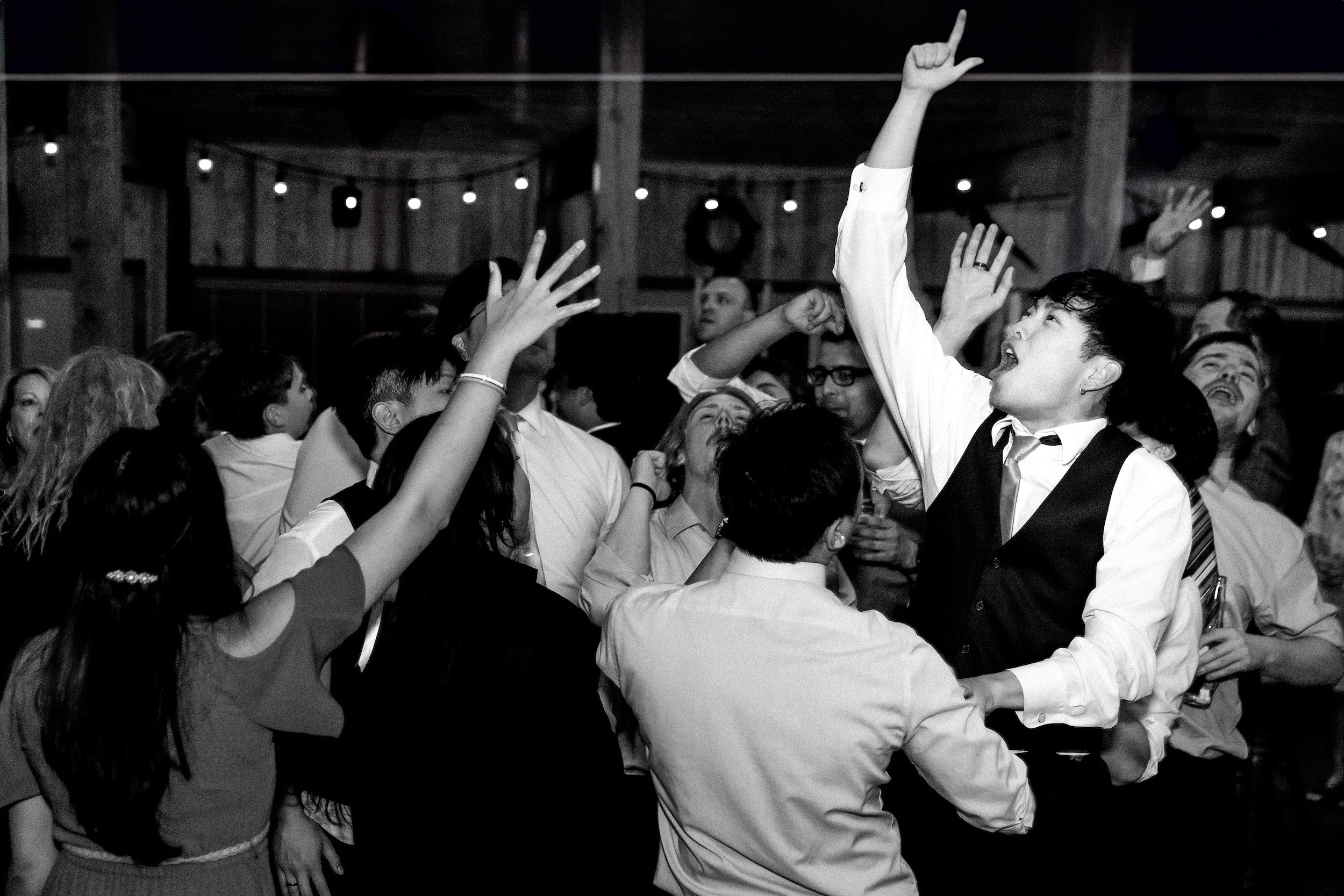 Packed dance floor at Auburn wedding reception with dramatic lighting