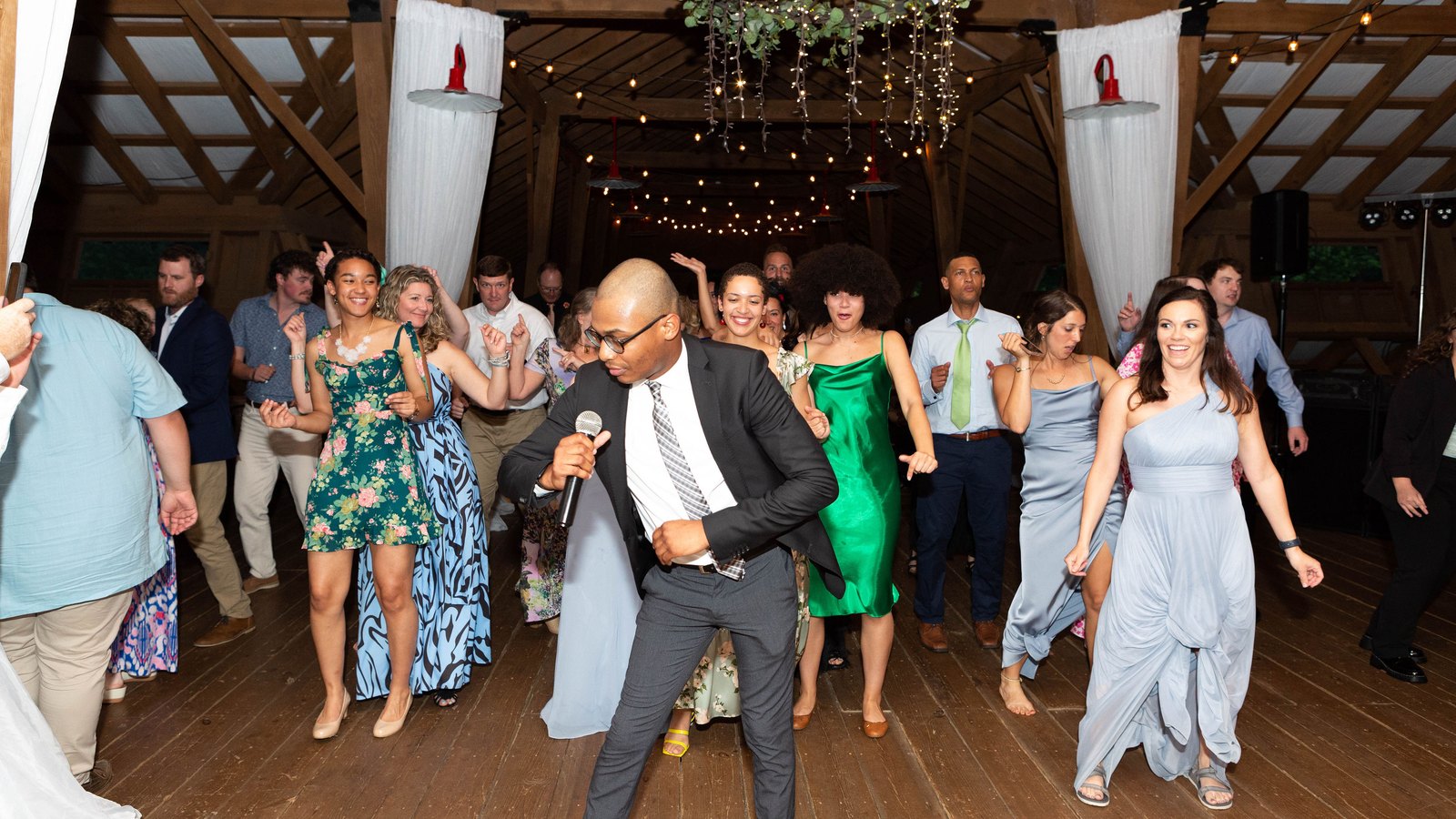 Auburn DJ on the mic leading a packed dance floor at a barn wedding reception near Auburn, AL