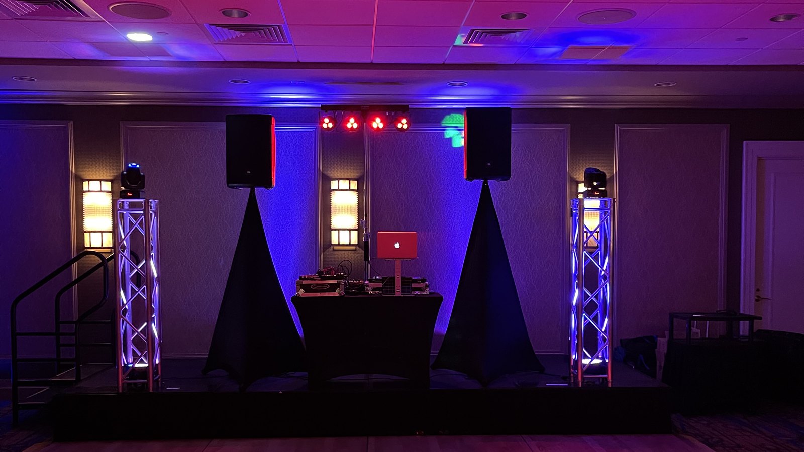 Auburn DJs professional setup with speakers, truss towers, and red and blue uplighting in a hotel ballroom