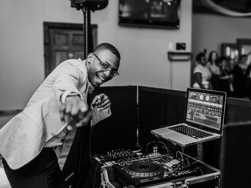 Auburn DJ smiling and pointing from behind the booth at a local wedding reception, black and white